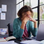woman sitting at her desk at work, stressed out. Mental health challenges in the workplace
