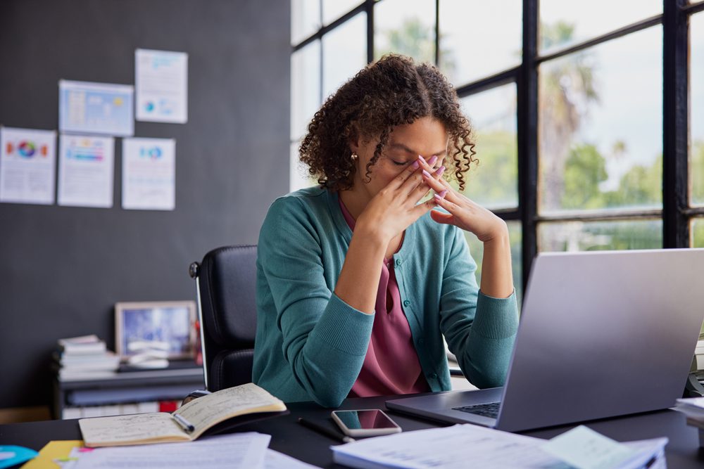 woman sitting at her desk at work, stressed out. Mental health challenges in the workplace