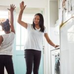 Mother and child smiling and giving each other a high five in a bright kitchen, celebrating a small accomplishment.