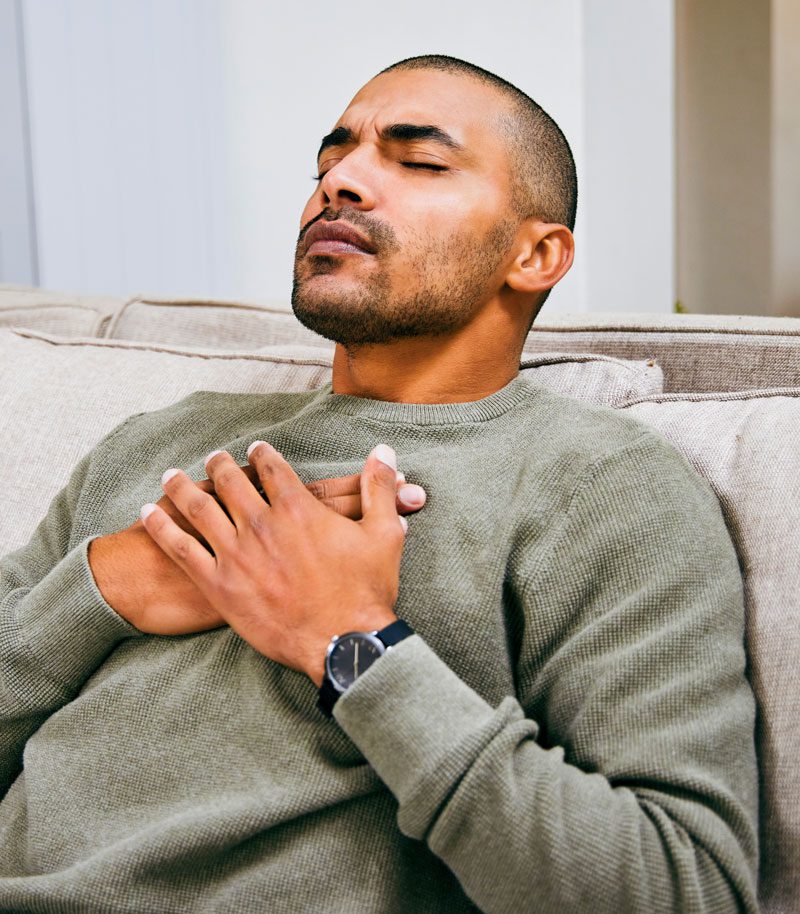Man sitting on couch practicing breathing techniques